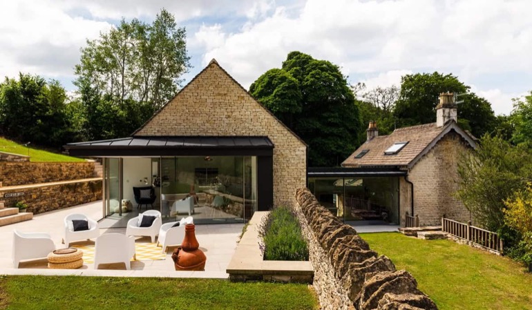 Stone cottages with contemporary glass extensions and outdoor terrace on a Cotswold hillside