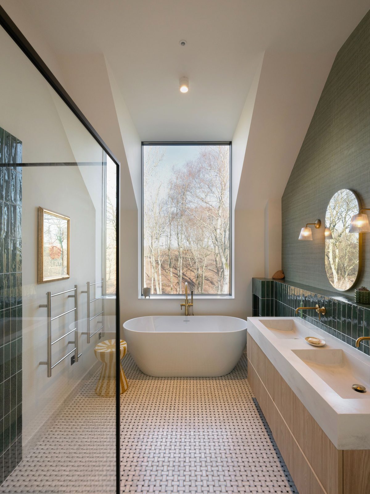 Bathroom with a freestanding bath beneath a tall window looking into the trees