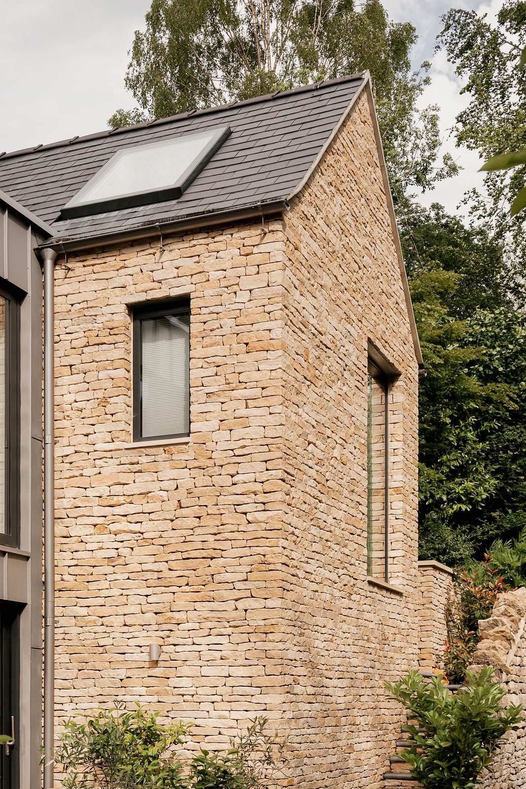 The new dry-stone gable and slate roof beside the original stone cottage